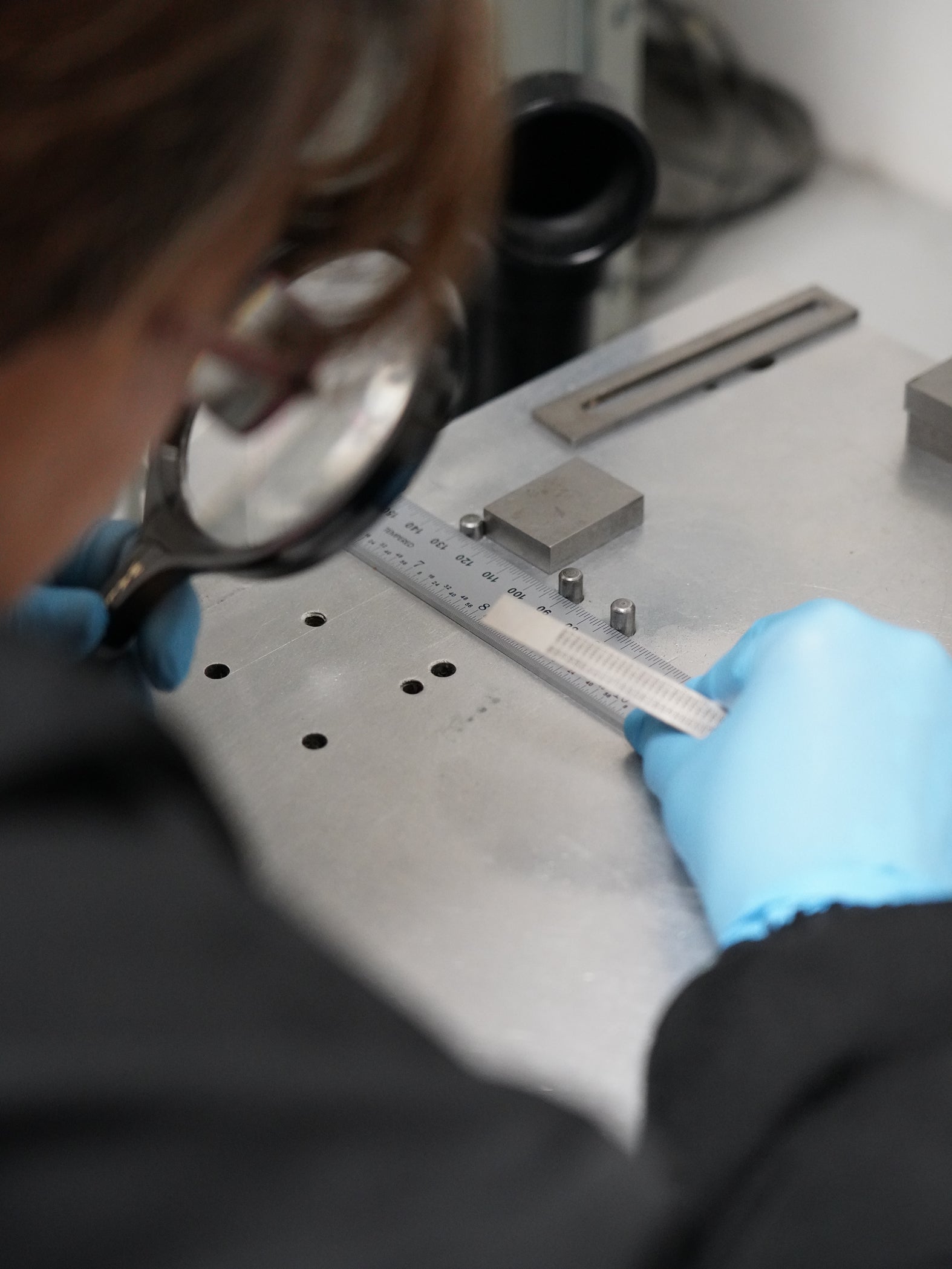 A PEC Tools stainless steel precision rule being verified under magnification for measurement accuracy